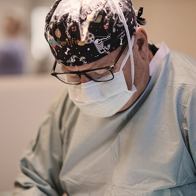 En person iført en maske og en sort hat.